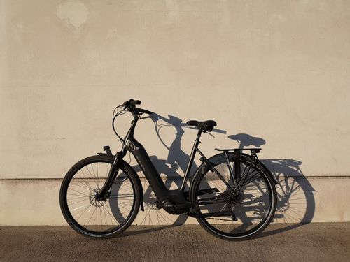 Free A sleek black bicycle parked against a sunlit wall casting a shadow. Stock Photo