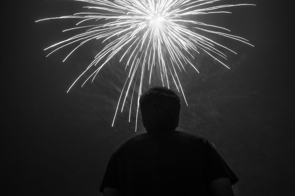 A person watching a dazzling fireworks display in Chennai, creating a dramatic silhouette effect.