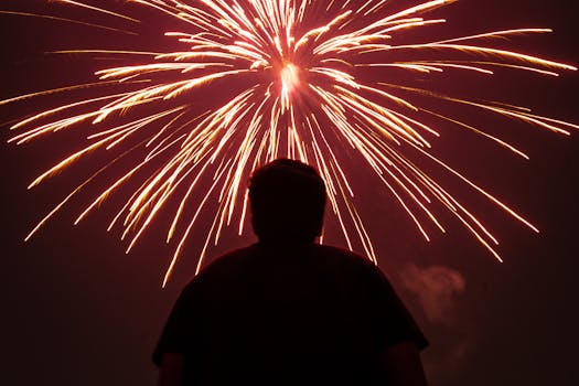 A captivating silhouette of a person watching vibrant fireworks in the night sky, creating a festive mood.