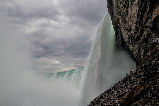 Powerful torrent cascading over Niagara Falls cliff during an overcast day.