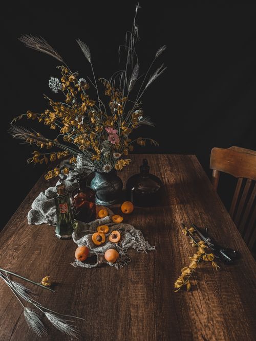 Free Wooden table with a rustic still life of flowers, fruits, and decor against a dark backdrop. Stock Photo
