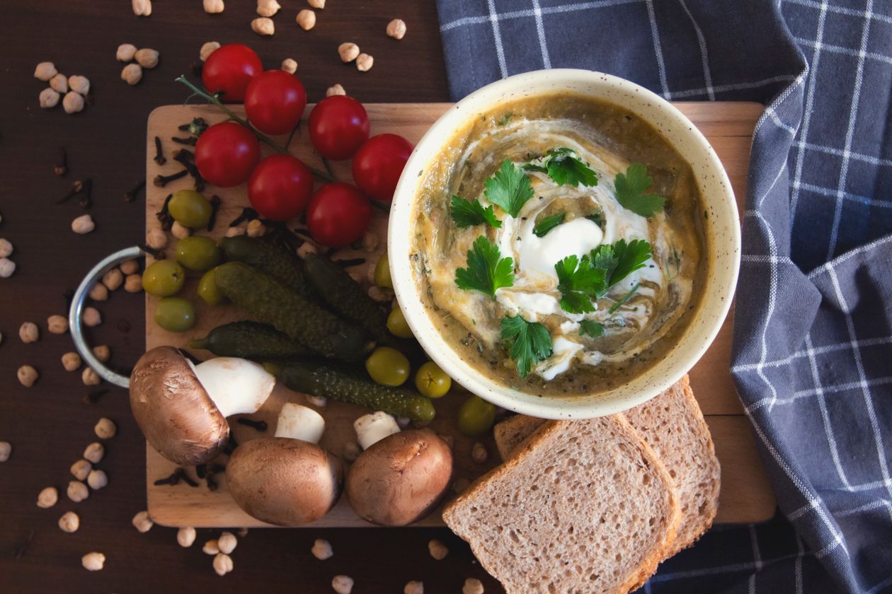 Vegetable beef soup served in white ceramic bowl with crusty bread