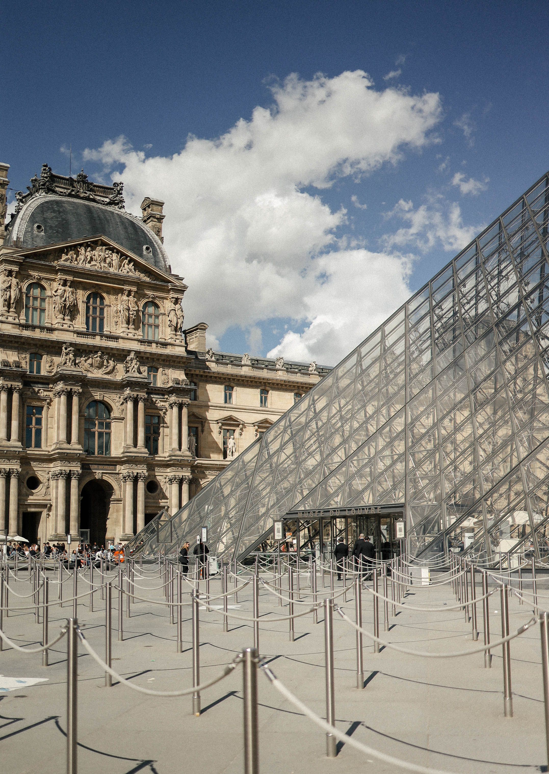 Exterior view of the Louvre Museum and its iconic glass pyramid in Paris.