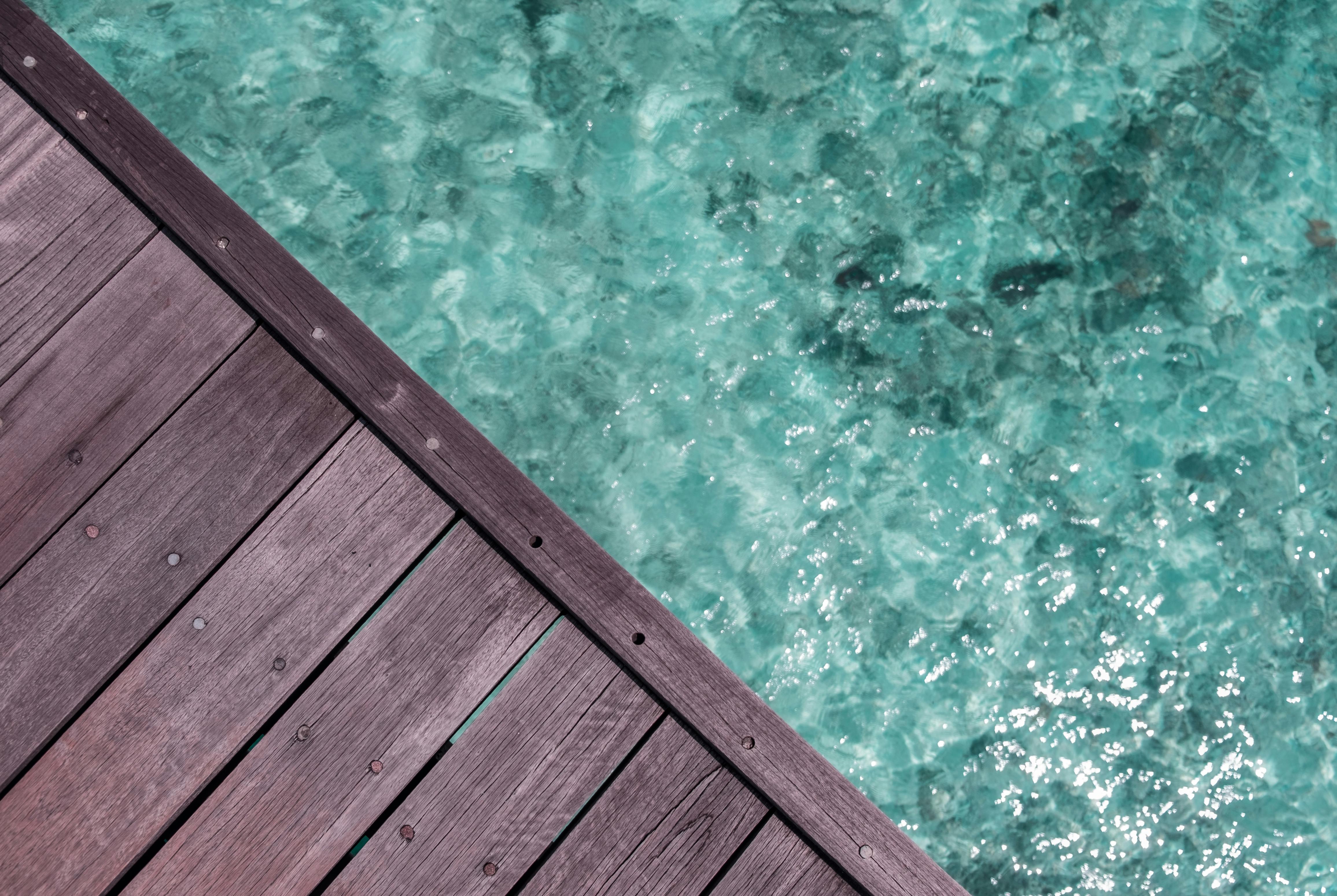 Free Close-up of a wooden dock with clear turquoise water below, providing a serene and tranquil vibe. Stock Photo