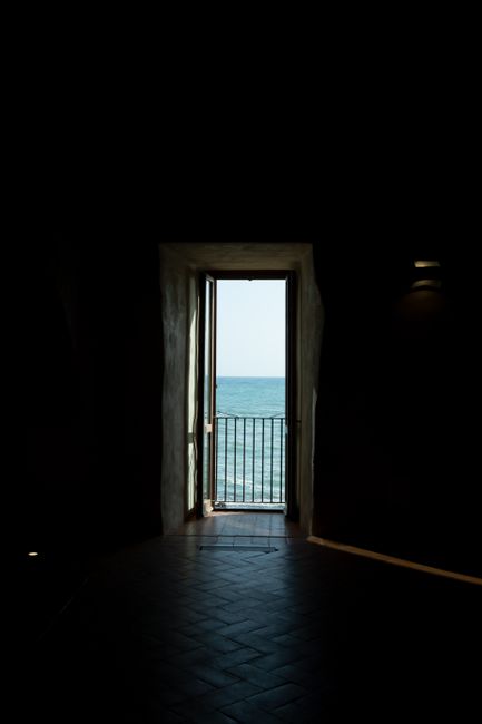 Silhouette of an open door revealing a calming ocean view, framed by shadows.