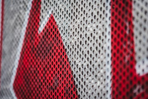 Free Detailed close-up of a perforated metal sheet painted in striking red and white colors. Stock Photo