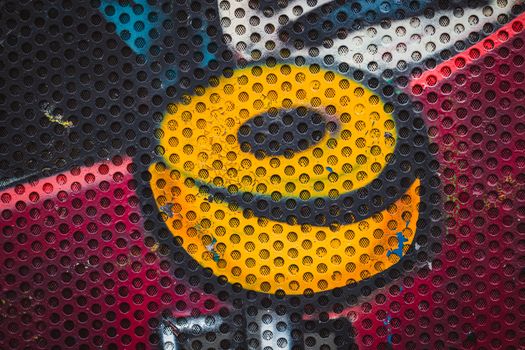 Vivid graffiti art with a perforated metal overlay, highlighting urban creativity.
