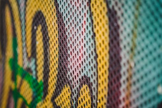 Close-up shot of vibrant graffiti art on perforated metal in Ostrava, Czechia.