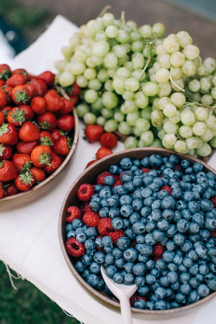 A vibrant assortment of fresh berries and grapes displayed on a white tablecloth, perfect for summer dining.