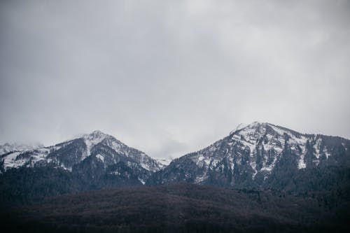 Snowy Mountain Tops Under a Cloudy Sky