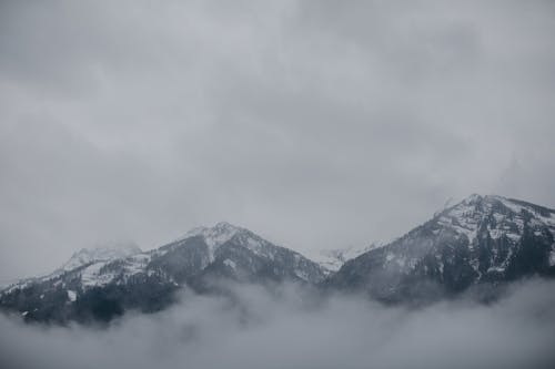 Snowy Mountain Tops in Fog Under a Cloudy Sky