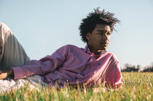 Man in a Pink Shirt Lying on a Field on a Sunny Day