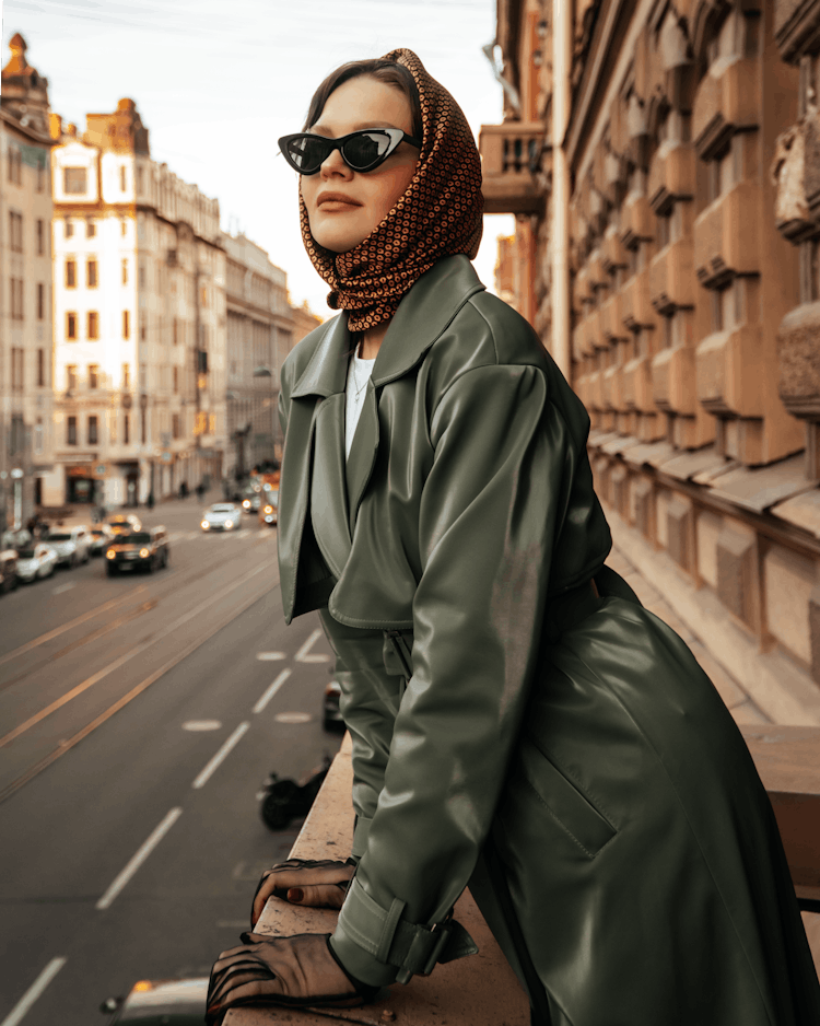 Woman In A Headscarf And Sunglasses Looking Over From A Balcony In City