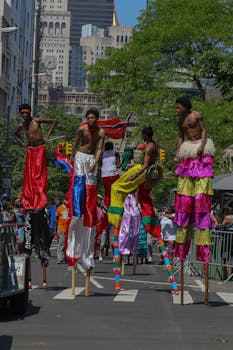 Vibrant parade in urban setting with costume-clad stilt walkers entertaining the crowd.