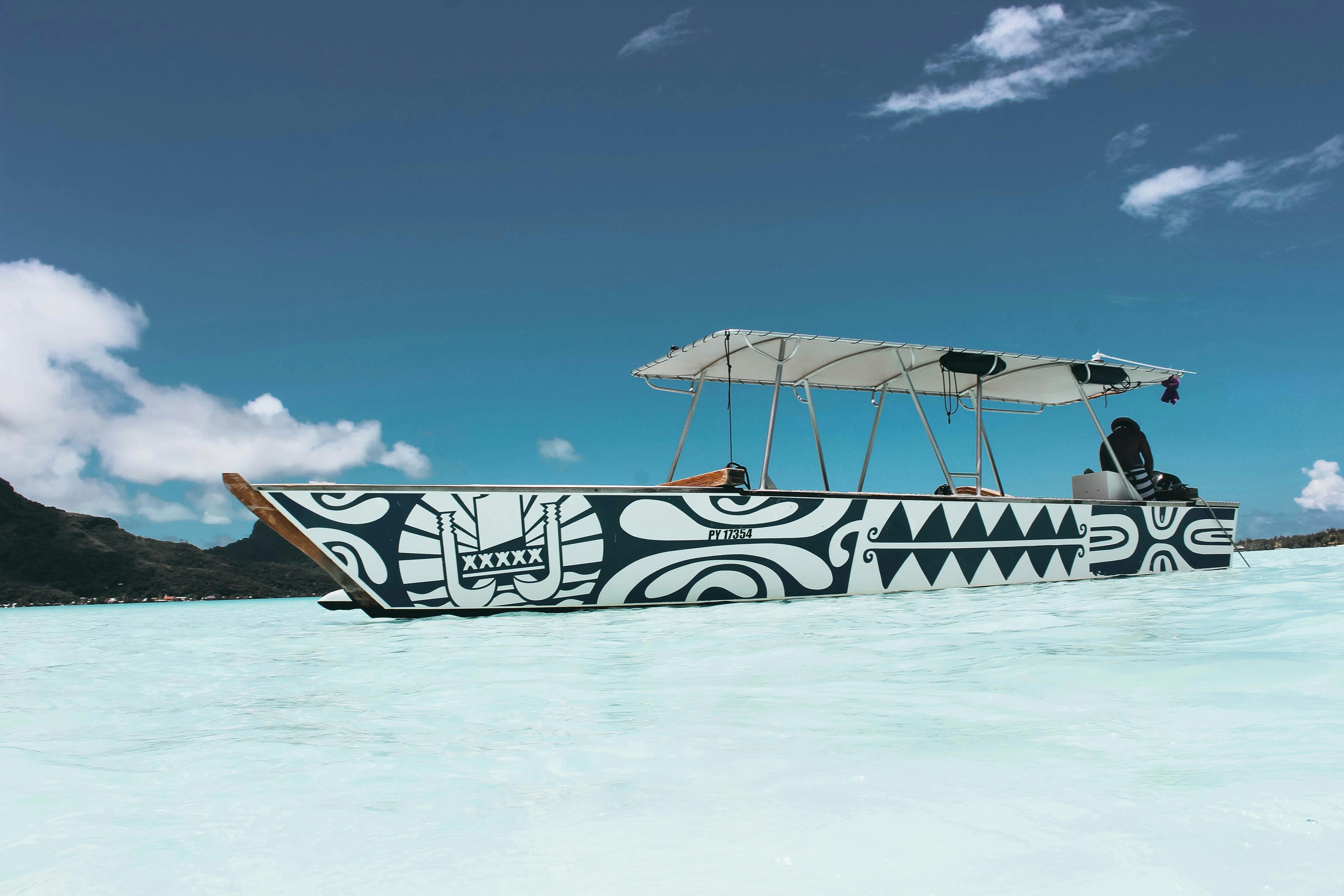 在法属波利尼西亚瓦伊塔普岛清澈的水面上，漂浮着装饰有部落图案的彩色船