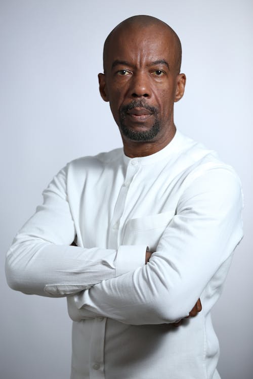 Photo of a Man in a White Shirt Posing with His Arms Crossed