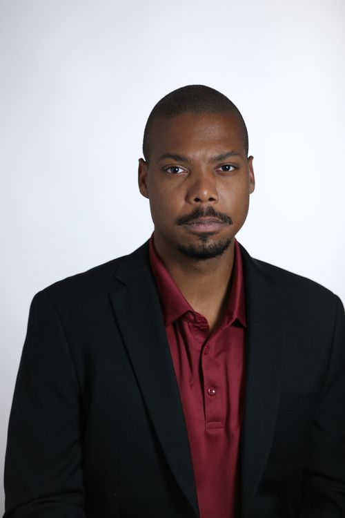 Free Portrait of a confident man wearing a black suit and red shirt against a white background. Stock Photo