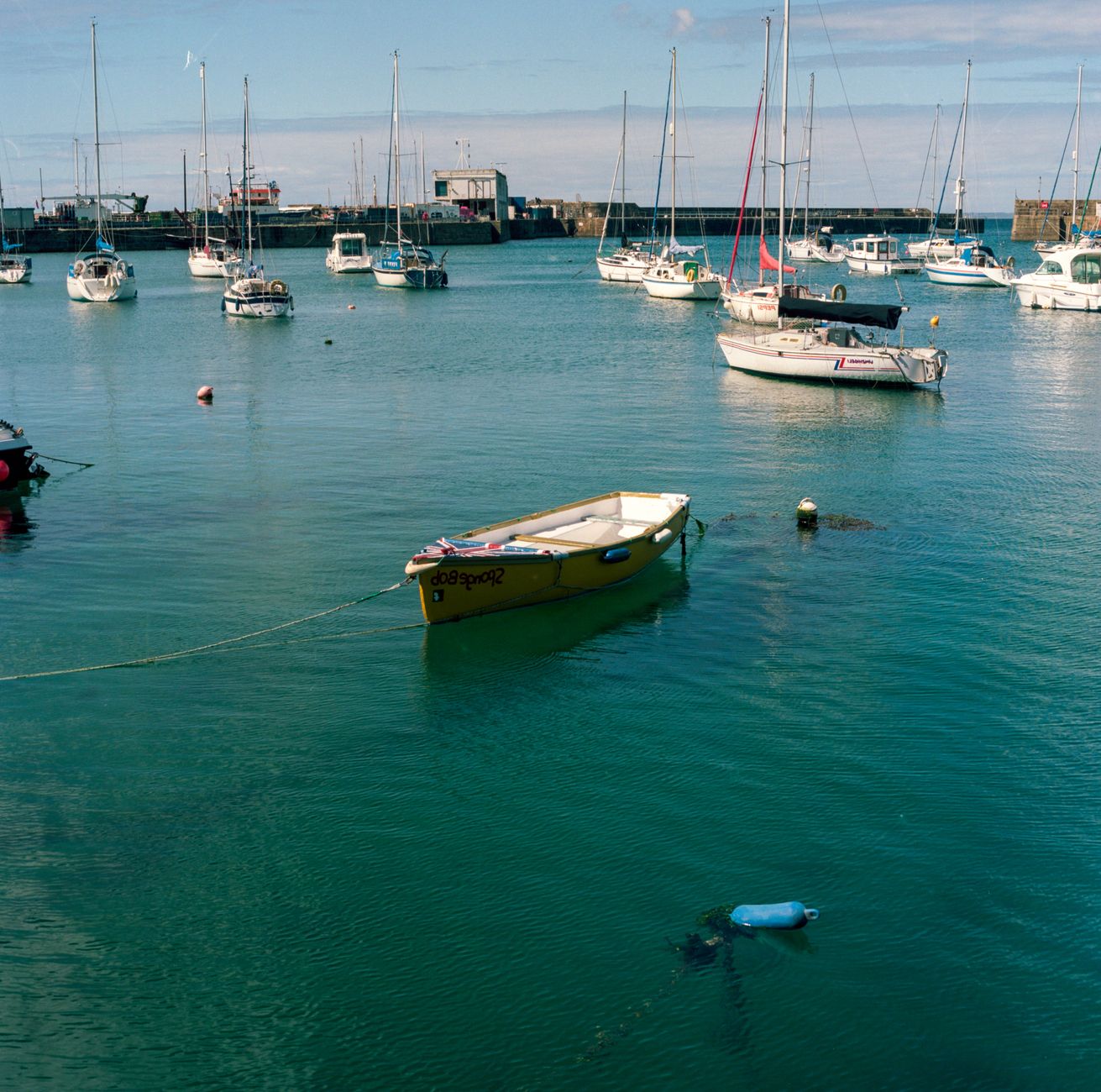 A peaceful scene of boats moored in a serene harbor under a clear sky.