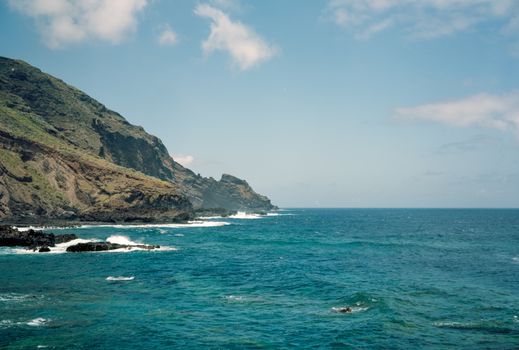 Breathtaking view of a coastal cliff meeting the vast blue ocean under a clear sky.
