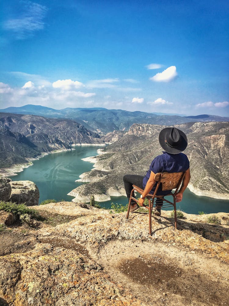 A Man Wearing Black Hat Sitting On The Chair