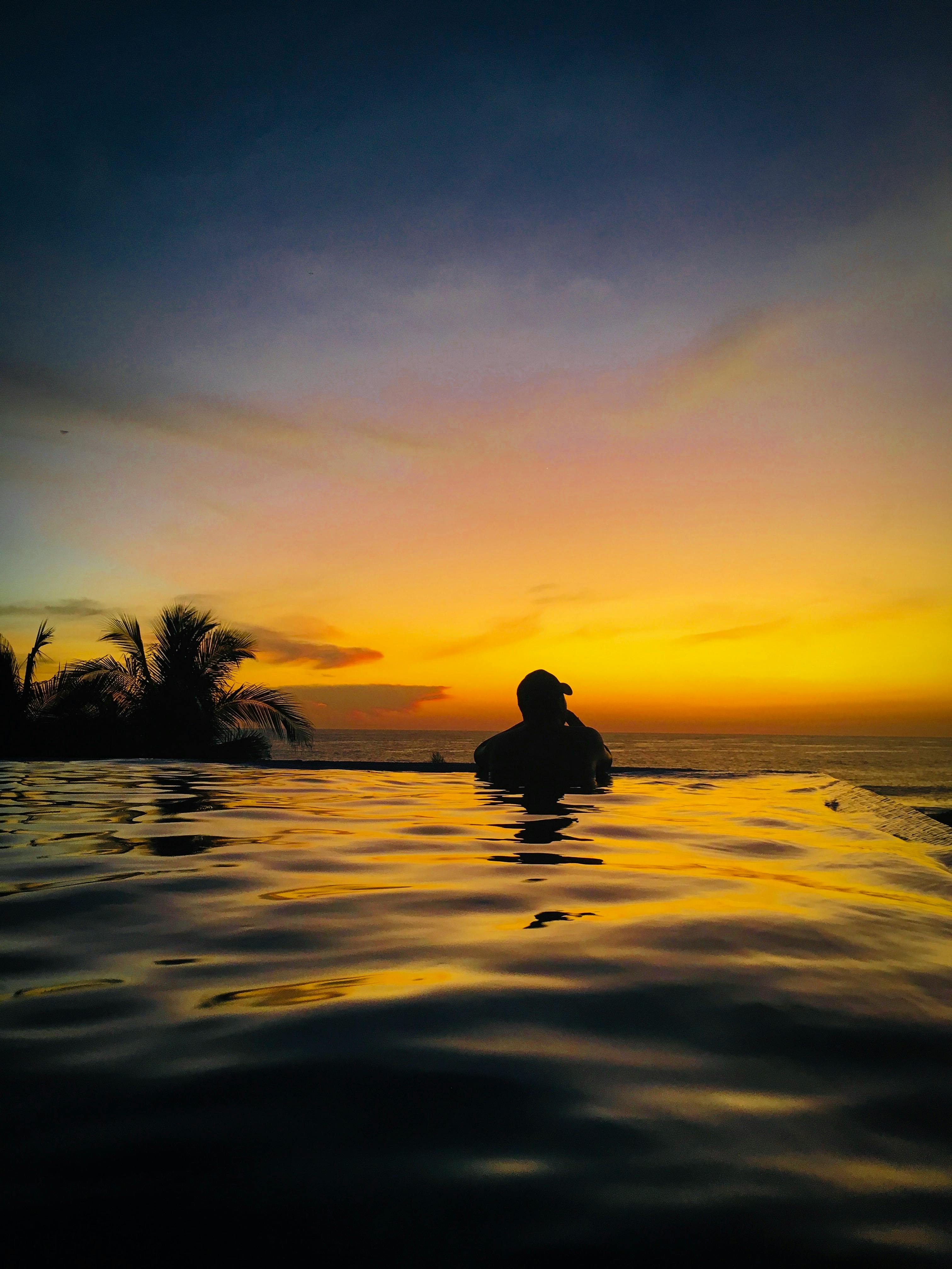 Couple at a clifftop infinity pool in Uluwatu watching sunset over the Indian Ocean at a luxury resort in Bali for couples