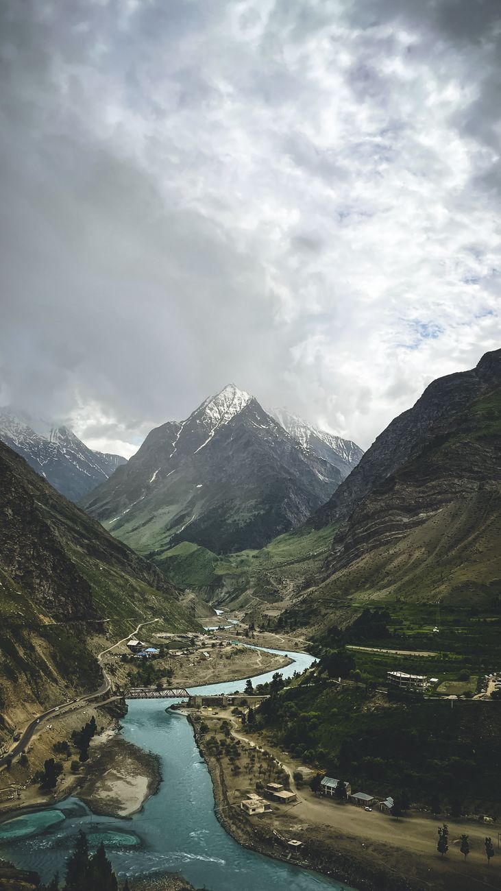 Aerial view of a stunning river winding through mountains in Lahul, India, under a cloudy sky.