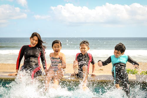 Vrouw En Drie Kinderen Die Water Spelen