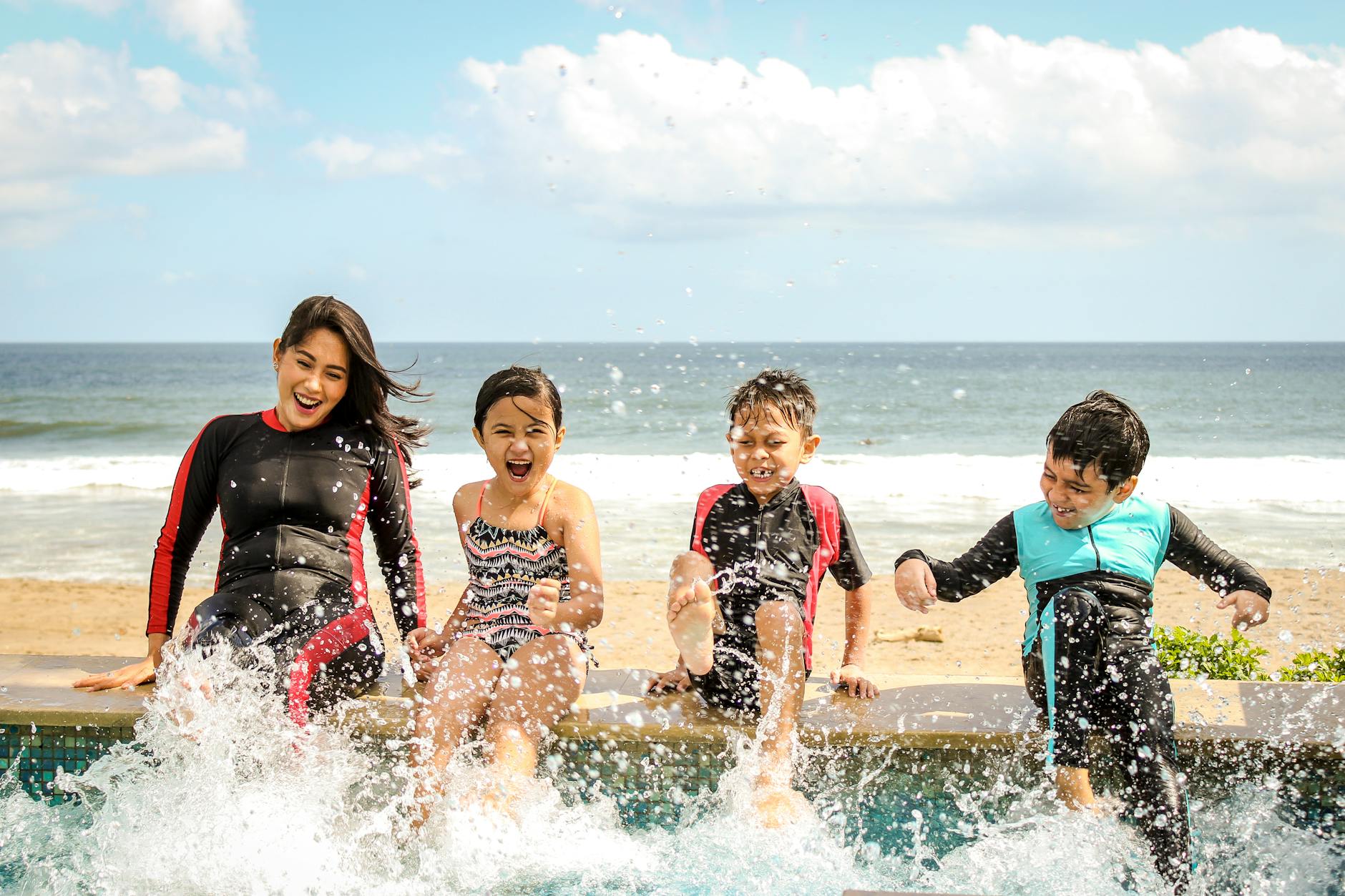 https://www.pexels.com/photo/woman-and-three-children-playing-water-1231365/