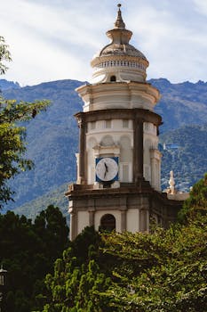 Stunning view of clock tower amidst lush greenery and mountains in Mérida, Venezuela.