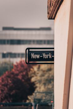 Close-up of a New York sign against a blurred urban backdrop with autumn colors.
