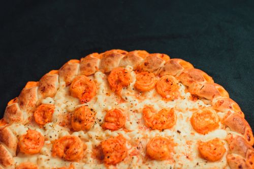Free Delicious cheese-crust pizza topped with juicy shrimp on a dark background. Stock Photo