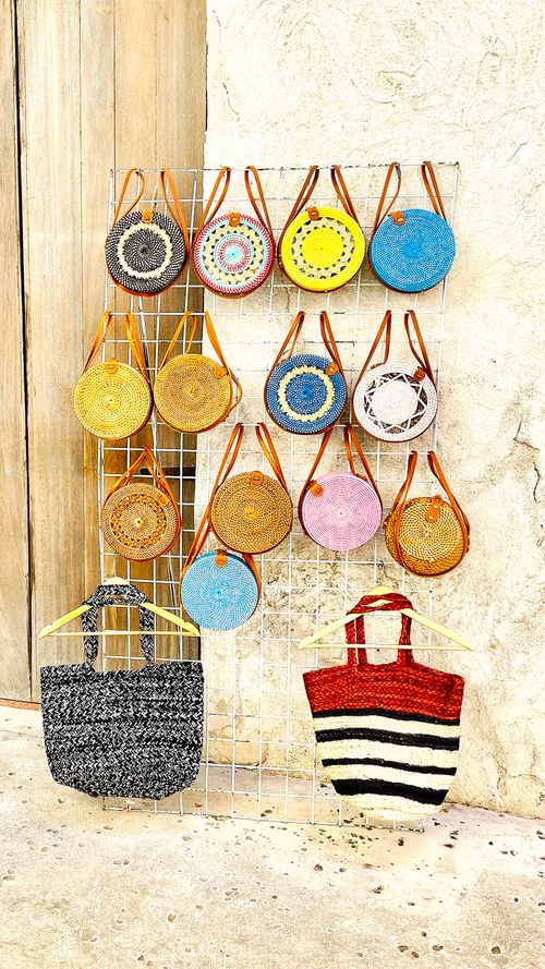 Free Vibrant collection of handcrafted bags displayed on a metal grid against a rustic wall. Stock Photo