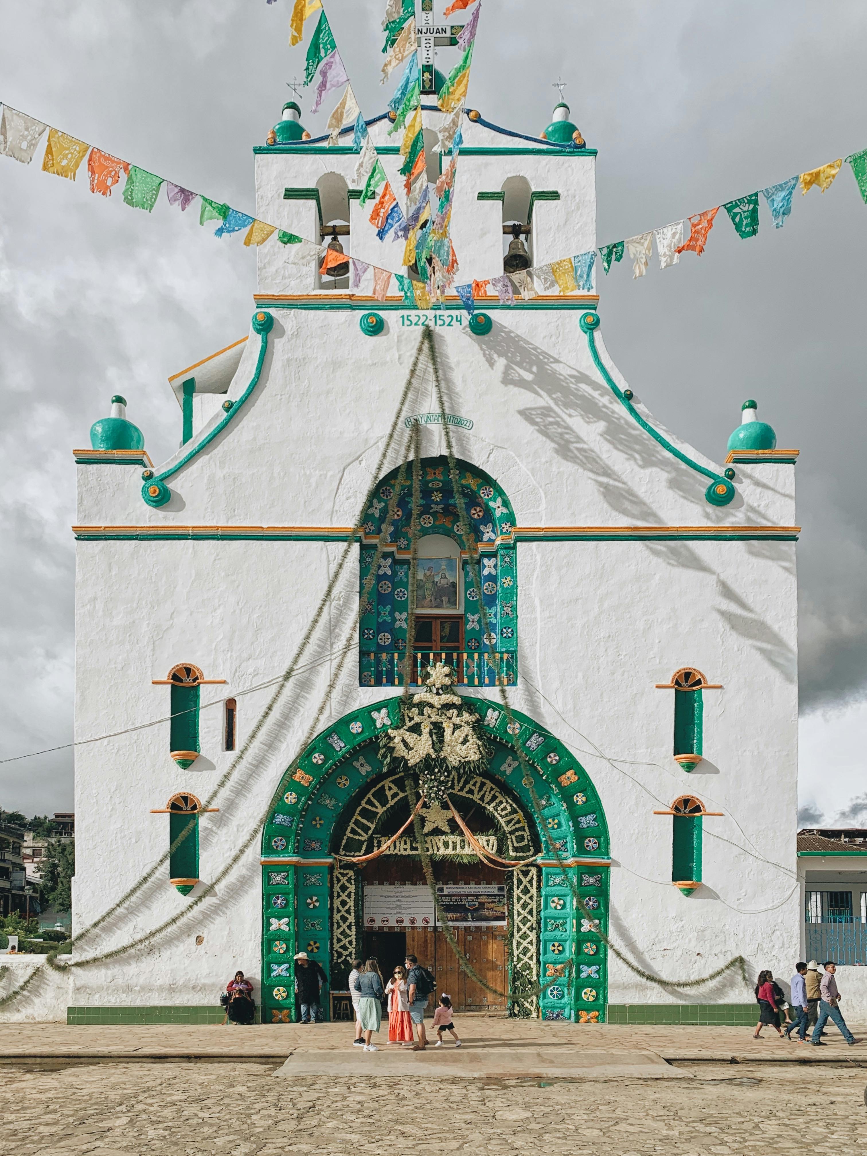 Vivid facade of a church in San Juan Chamula, Mexico, with traditional decorations and festive flags.