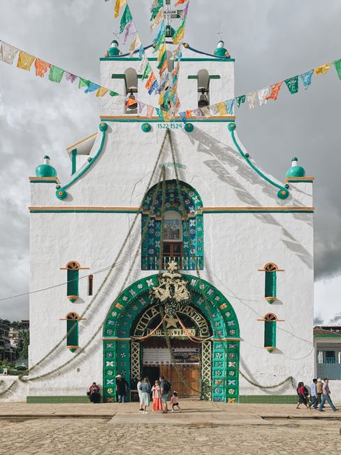 Vivid facade of a church in San Juan Chamula, Mexico, with traditional decorations and festive flags.