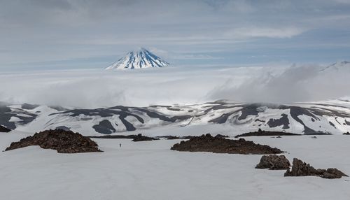 Free Stunning snowy landscape featuring a distant volcano peak amidst clouds. Captivating nature scene. Stock Photo