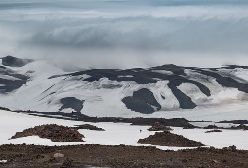 Free Dramatic snowy mountains under a cloudy sky, showcasing rugged terrain and ice formations. Stock Photo
