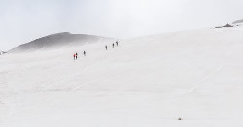 People Walking on Snow Covered Mountain
