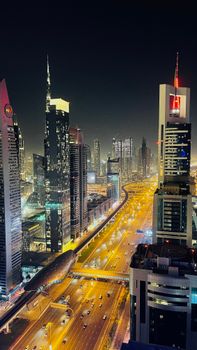 Captivating aerial night view of skyscrapers and highways in Dubai's urban landscape.
