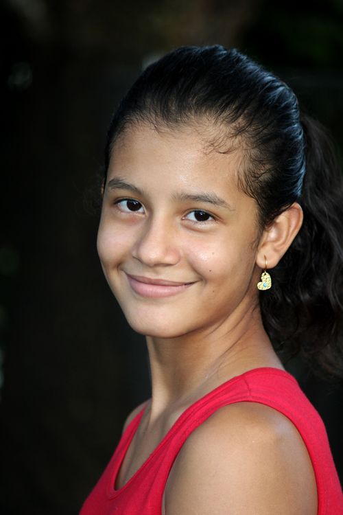 Free Close-up portrait of a smiling young woman in a red dress with earrings outdoors. Stock Photo