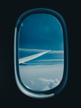 A serene view from an airplane window featuring a wing and clear blue sky.