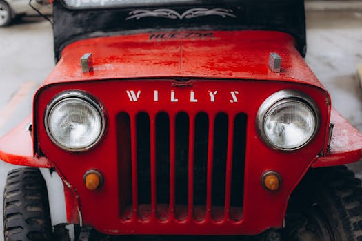 Detailed view of a vintage red Willys jeep showcasing its classic design and front grille.