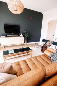 Elegant modern living room featuring a leather sofa, black accent wall, and minimalist decor.