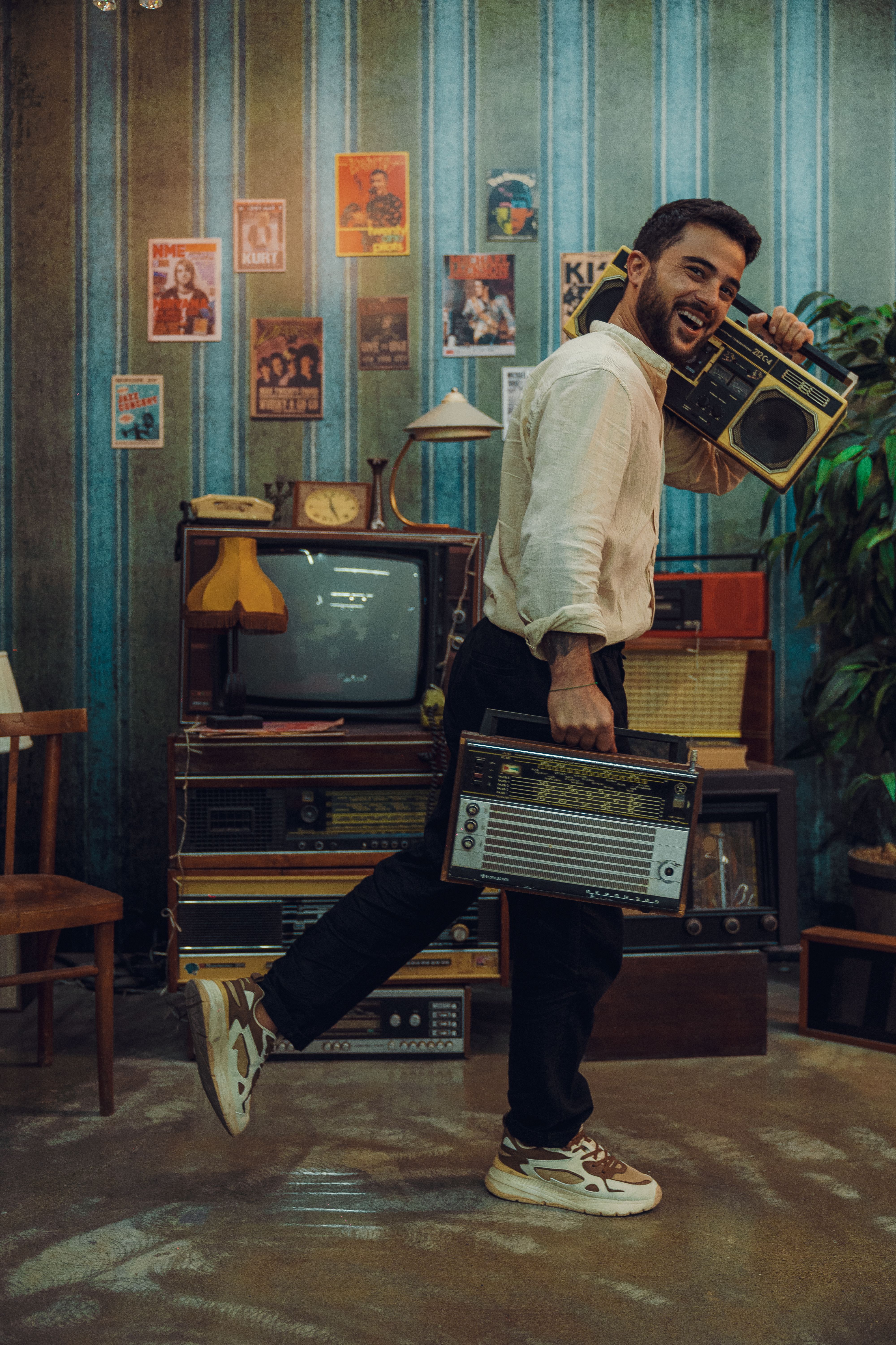 Man joyfully holding vintage radios in a retro living room setting with classic decor.