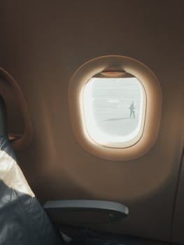 Sunlit airplane interior with a view through the window onto the tarmac.