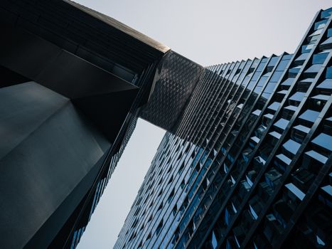 Low angle view of a modern skyscraper showcasing unique architectural design with glass reflections.