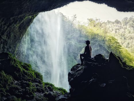 Silhouette of a person exploring a lush waterfall cave in Mexico's natural beauty.