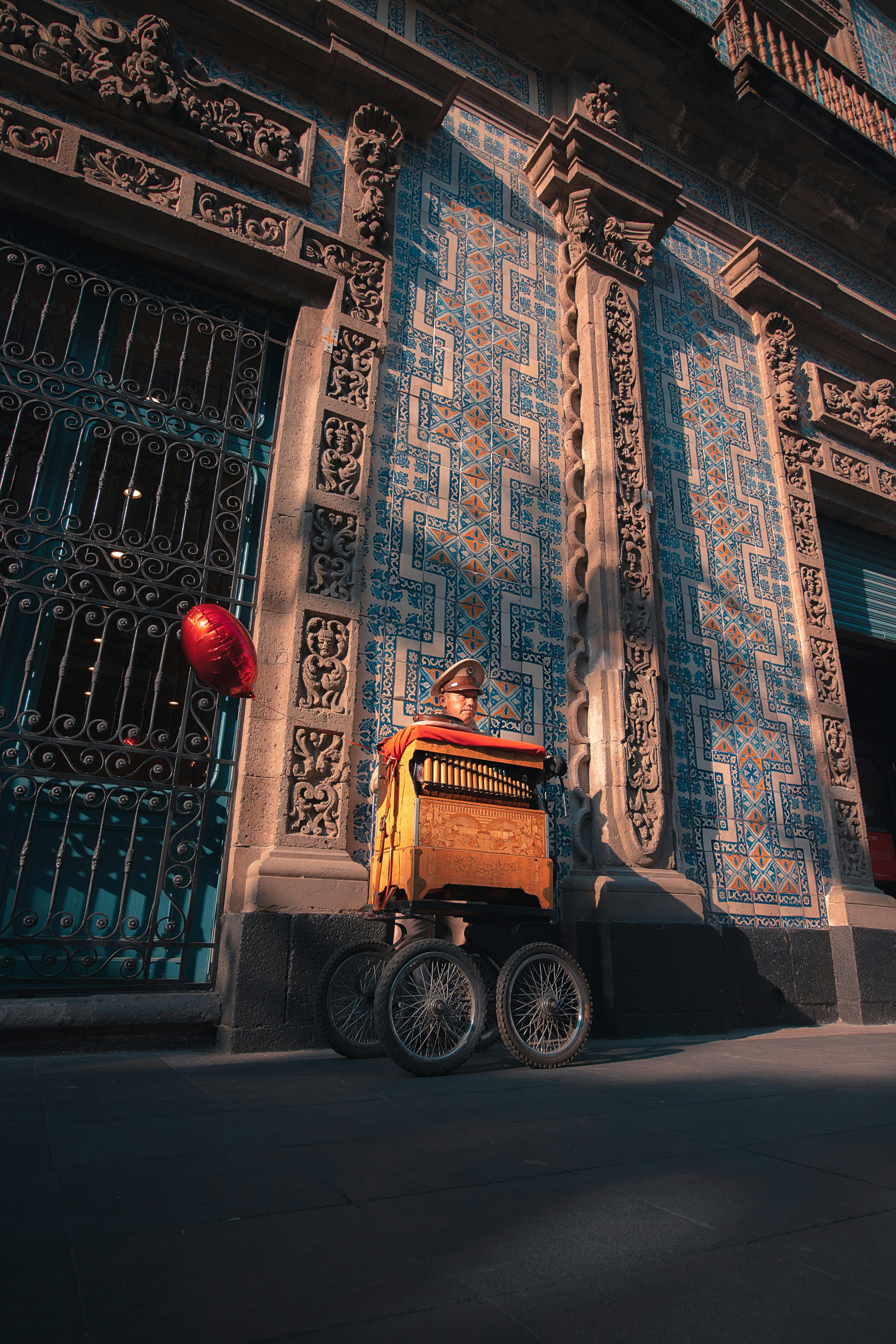 A street musician with a barrel organ in front of historic architecture in Mexico City.