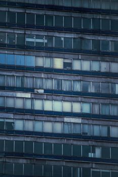 Weathered facade of a high-rise apartment building in Mexico City with various window patterns.