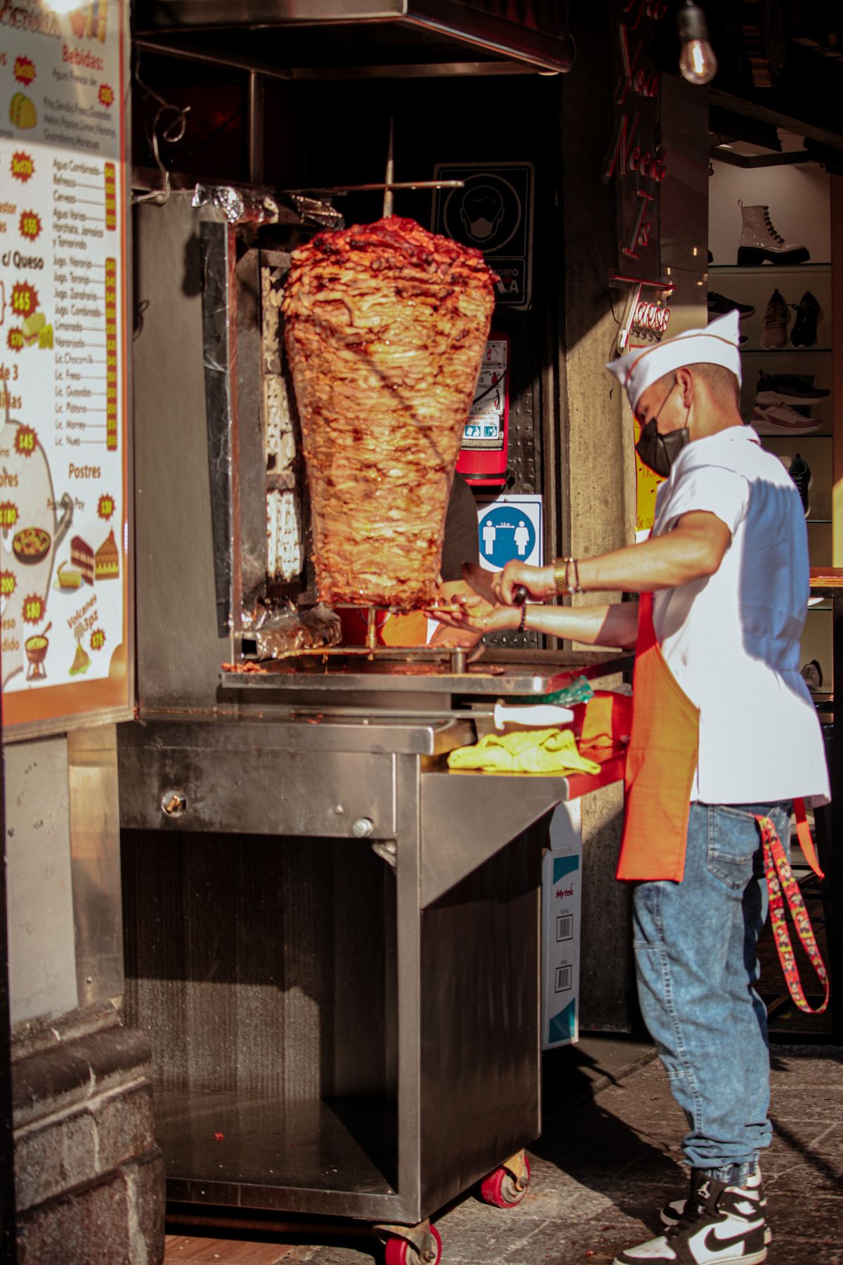 A street vendor prepares traditional tacos al pastor in Mexico City, showcasing vibrant Mexican culinary culture.