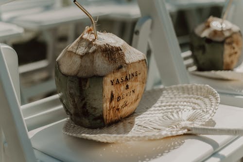 Coconut with Drinking Straw and Hand Fan on Chair